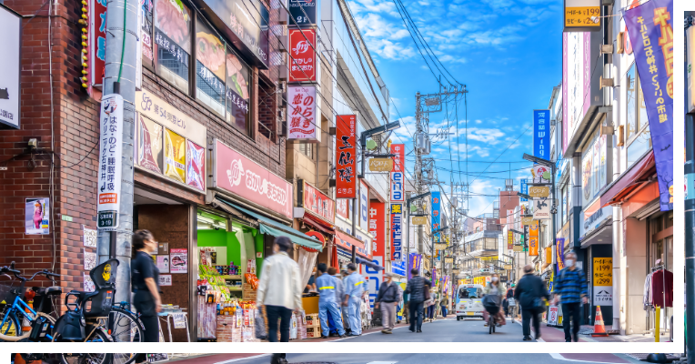 日本の都市部にある賑やかな商店街の通り。多くの看板や電線が張り巡らされた活気ある風景