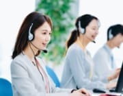 ヘッドセットを着用してコンピューターで作業している3人の人物