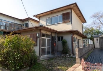 日当たりの良い、やや古びた2階建ての日本家屋の正面外観